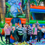 Na zdjęciu widać dzieci z grupy MISIAKÓW, dzieci stoją na dworze, przy dmuchańcu. Jest to zdjęcie grupowe.