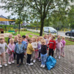 Na zdjęciu widać dzieci z grupy MOTYLKÓW, dzieci są na dworze, stoją z workiem uzbieranych odpadów. Jest to zdjęcie grupowe.