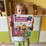 Na zdjęciu widać Julkę, dziewczynka trzyma nową książkę "Prawdziwe Księżniczki".