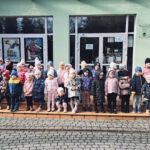 Na zdjęciu widać dzieci z grupy SŁONECZEK i MISIAKÓW. Dzieci stoją na dworze, przed MDK w Lublińcu. Jest to zdjęcie grupowe.