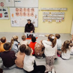 Na zdjęciu widać dzieci z grupy BIEDRONEK oraz panią Weronikę z Lubiteki. Dzieci siedzą na dywanie i słuchają zajęć.
