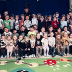 Na zdjęciu widać dzieci z grupy BIEDRONEK, JEŻYKÓW I MOTYLKÓW oraz Panią Irenę - emerytowaną górniczkę. 
Jest to zdjęcie grupowe.