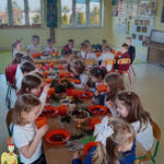 Na zdjęciu widać dzieci z grupy JEŻYKÓW, dzieci siedzą przy stole wigilijnym i jedzą świąteczne potrawy.
