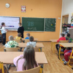 Na zdjęciu widać dzieci z grupy BIEDRONEK, dzieci są w SP4 w Lublińcu, w jednej z klas, siedzą w ławkach.