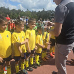 Na zdjęciu widać chłopców z grupy JEŻYKÓW i BIEDRONEK, chłopcy są ubrani w stroje sportowe i dostają medal.