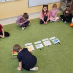 Na zdjęciu widać dzieci z grupy JEŻYKÓW, dzieci siedzą na dywanie w sali i uczestniczą w zajęciach dydaktycznych.